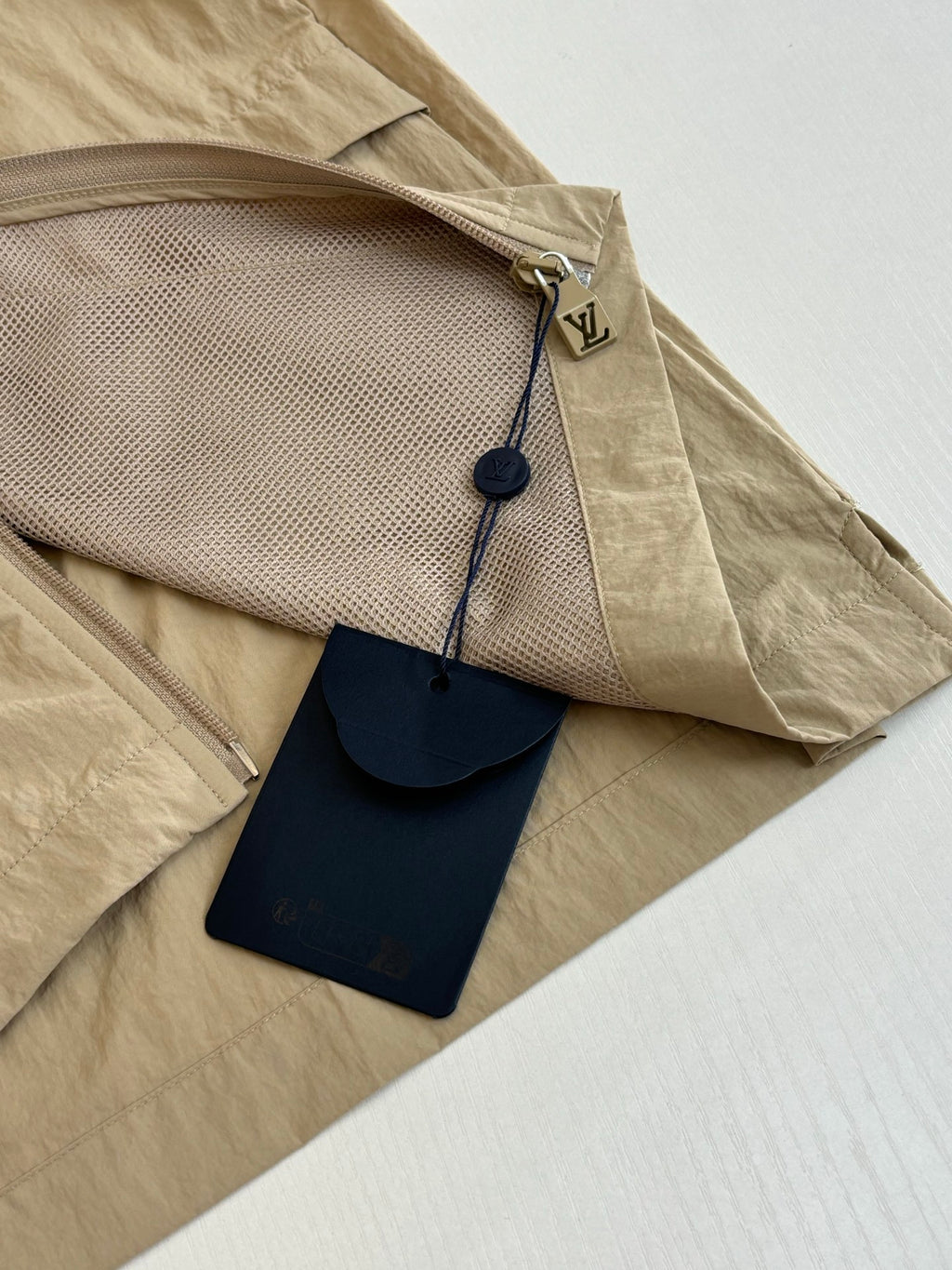 Beige Louis Vuitton jacket with zip pocket and hanging leather tag