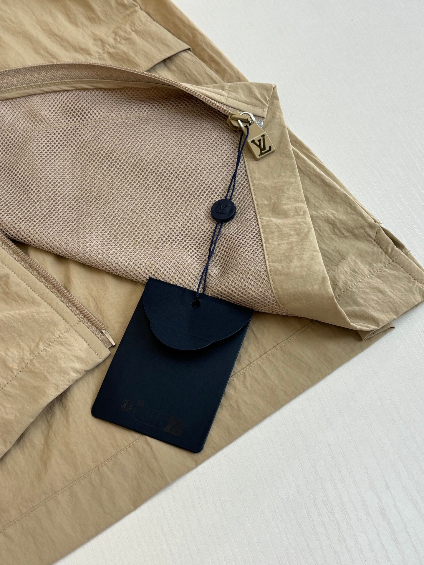 Beige Louis Vuitton jacket with zip pocket and hanging leather tag
