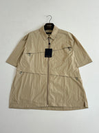 Beige short-sleeve zip jacket with pointed collar and visible logo hangtag
