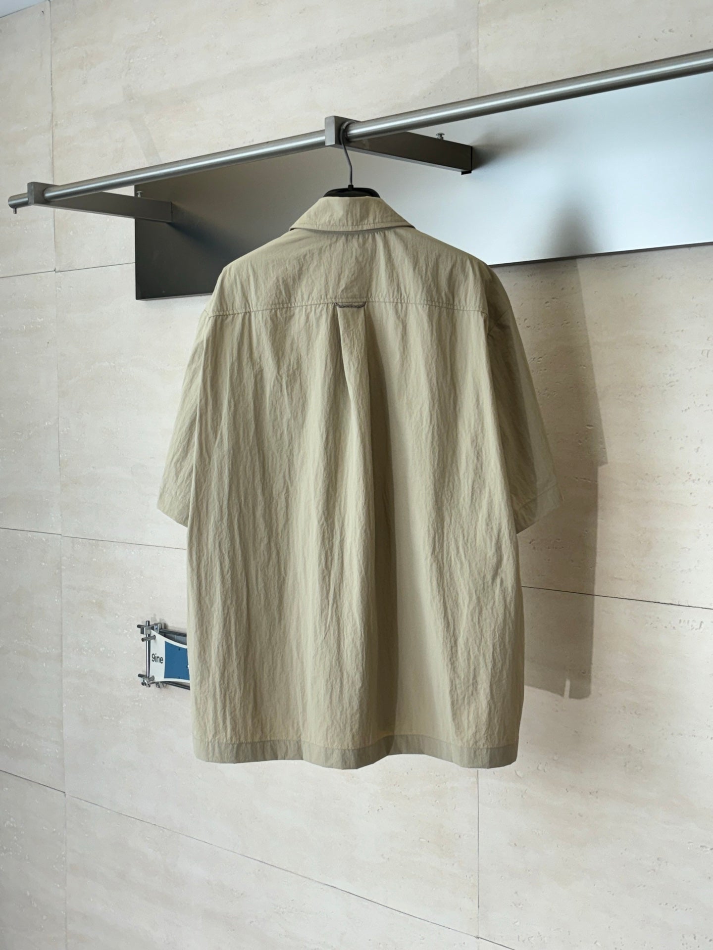 Beige short-sleeve utility jacket, back view with yoke seam and center zipper