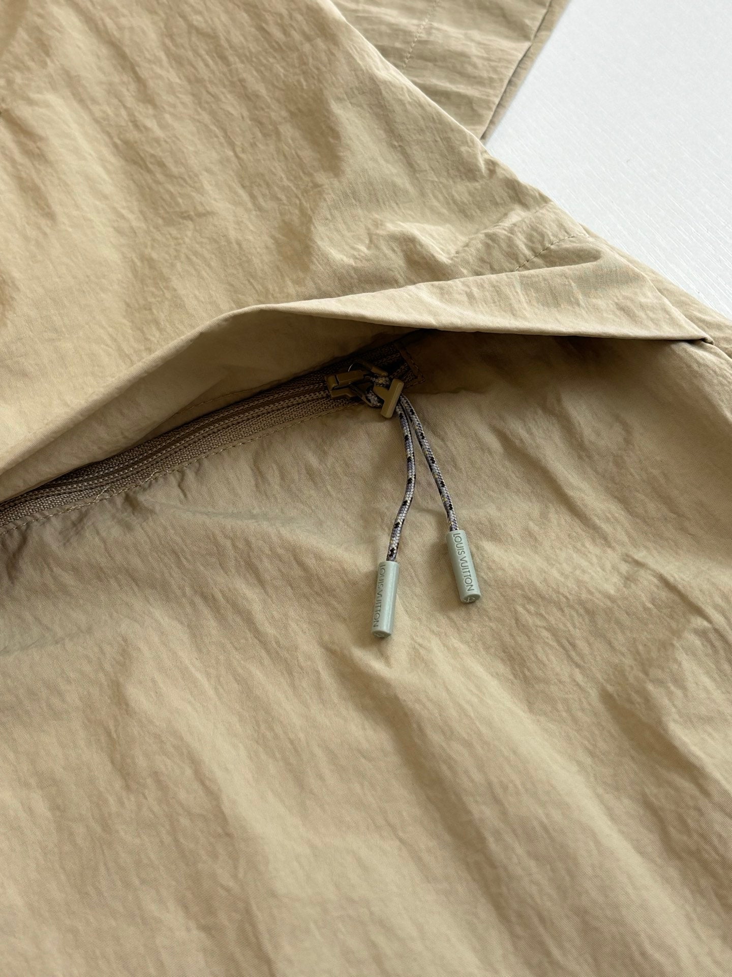 Beige Louis Vuitton jacket with mesh-lined pocket opening and drawstring pulls