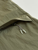 Olive green jacket sleeve cuff with zipper pull and drawstring detail.