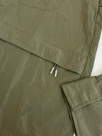 Olive green jacket back hem with zipper and layered fabric trim.