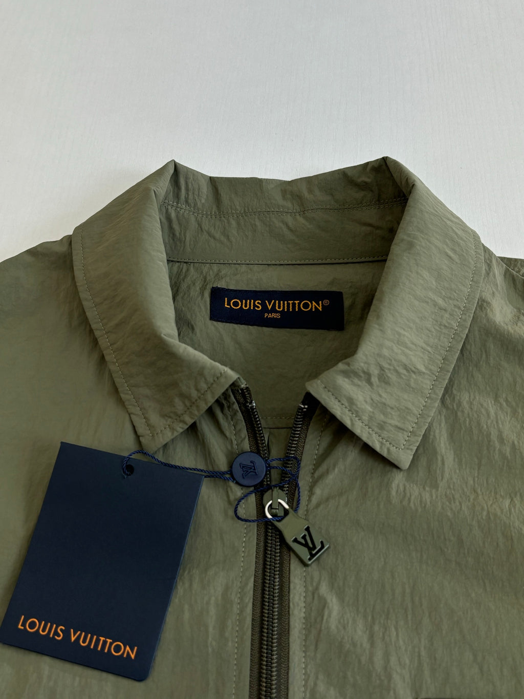 Olive green jacket collar with front zipper and Louis Vuitton label tag.