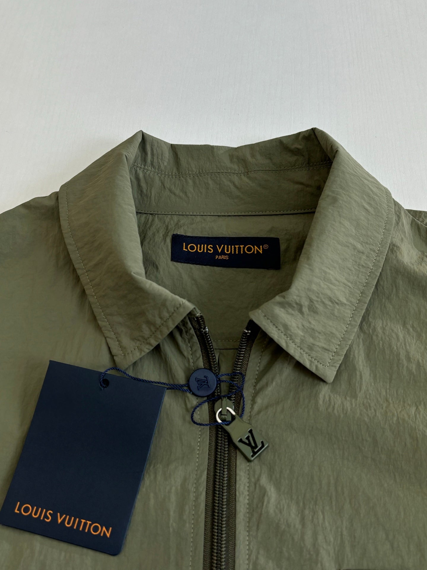 Olive green jacket collar with front zipper and Louis Vuitton label tag.