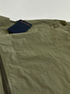 Olive green jacket front with zipper and interior pocket label tags.