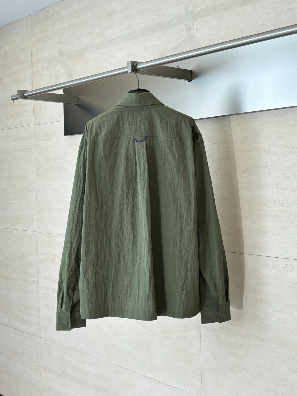 Olive green jacket, back view, with stand collar and partial seam detailing.