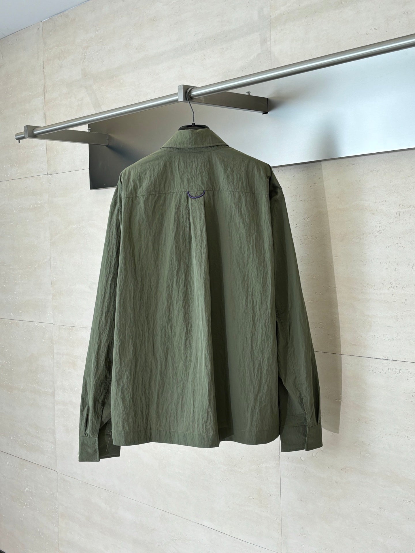 Olive green jacket, back view, with stand collar and partial seam detailing.
