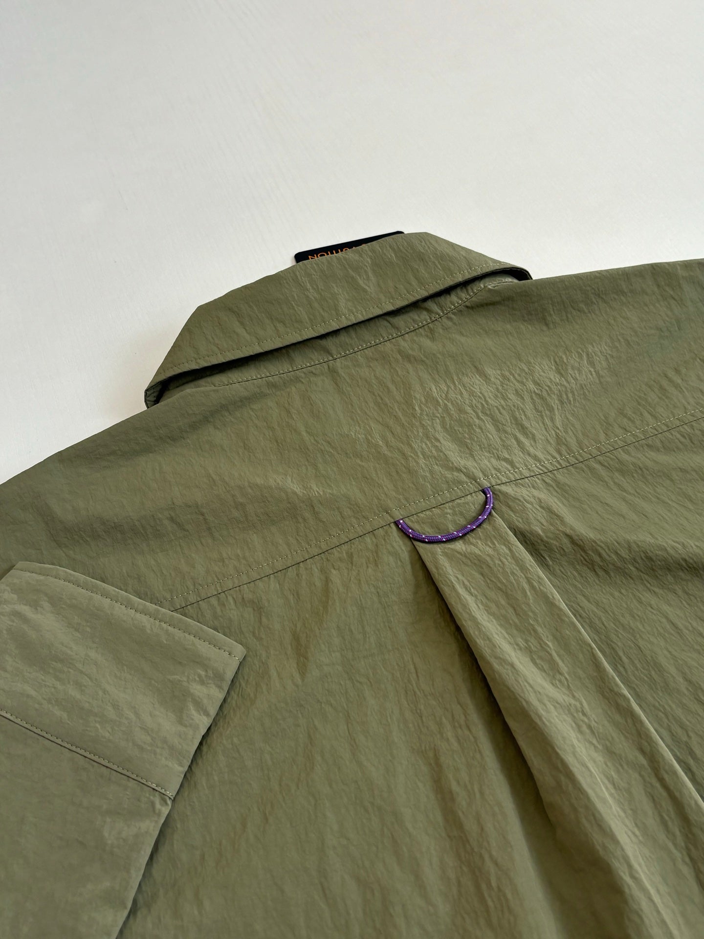 Olive long-sleeve jacket with flap collar and purple trim detail