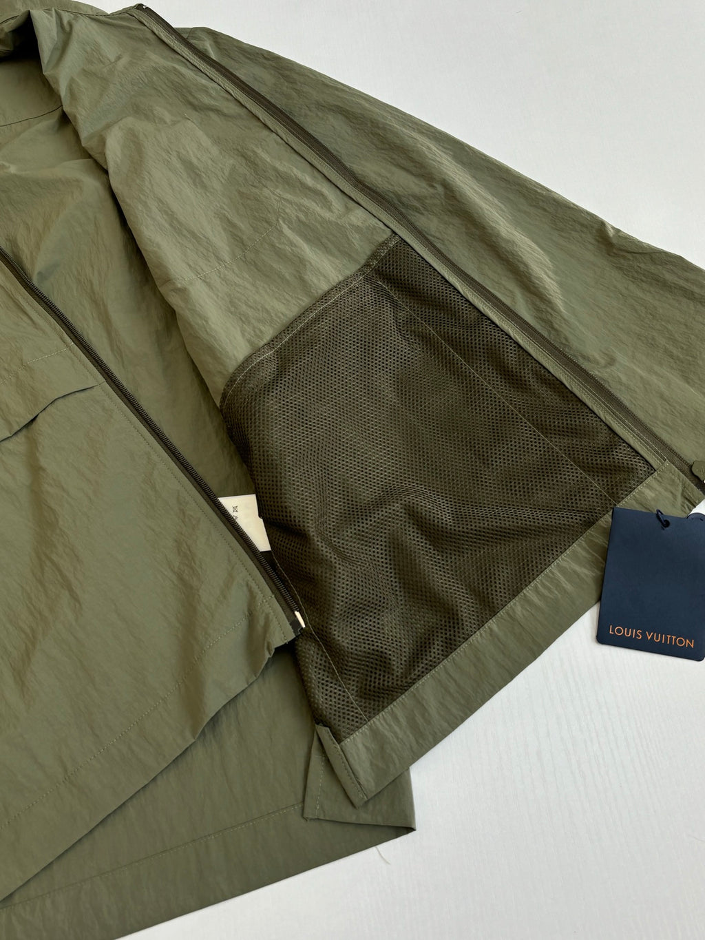 Olive green jacket with large interior mesh panel and zipper closure.