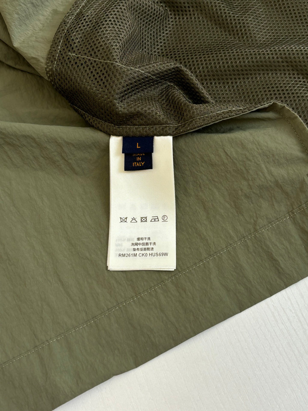 Olive jacket showing inner mesh lining and white size label tag