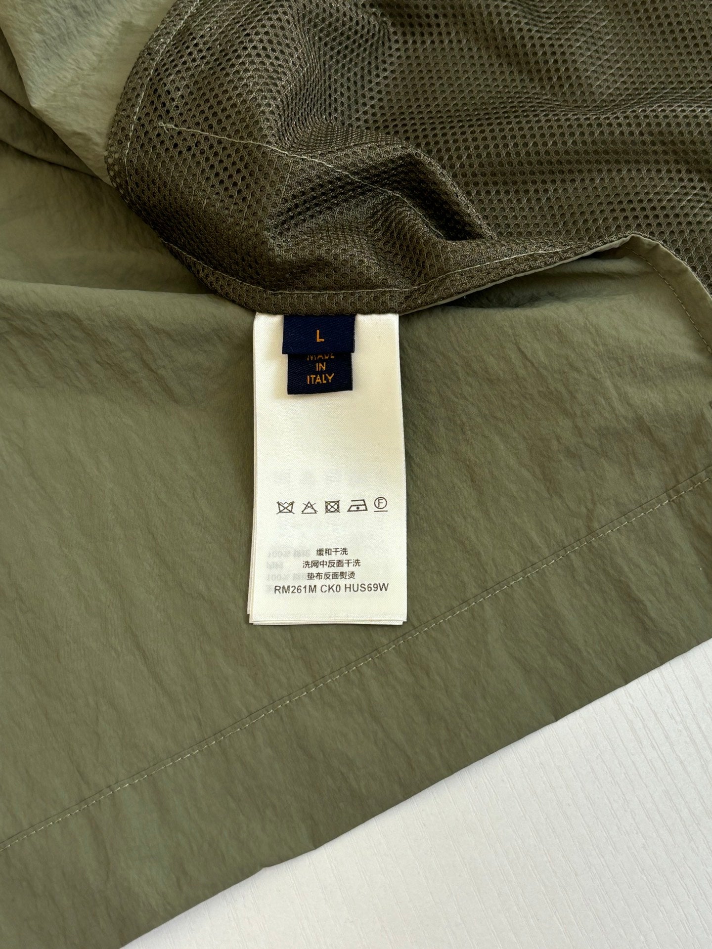 Olive jacket showing inner mesh lining and white size label tag