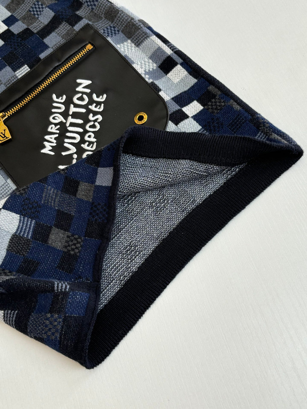 Louis Vuitton shorts close-up: black trim, blue-gray check pattern, logo pocket corner