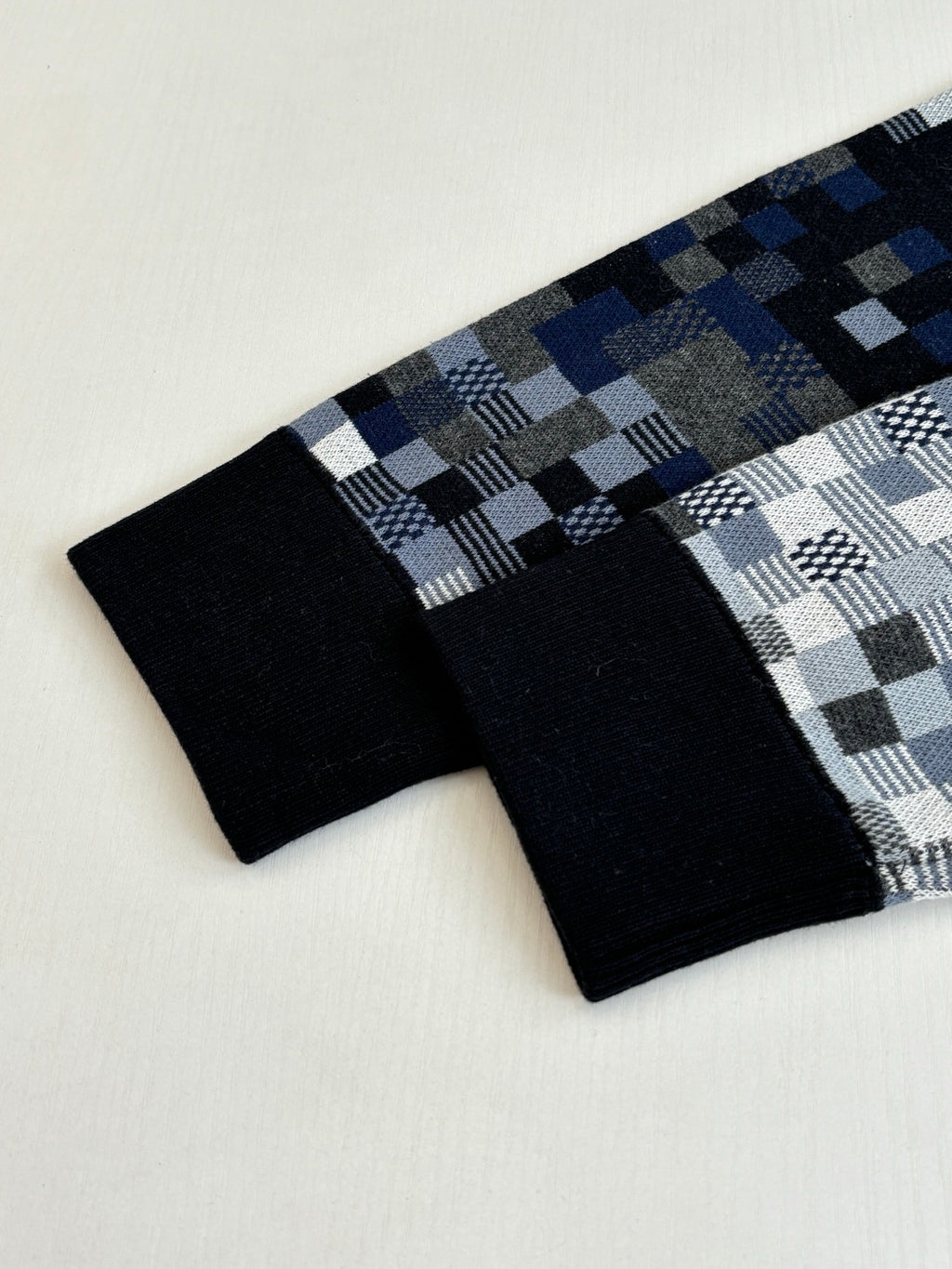 Folded check knit and black fabric cuff details in blue, white, and dark tones