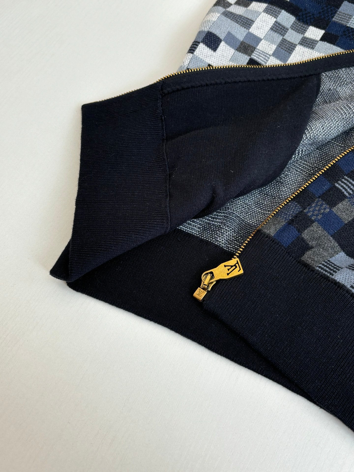 Sleeve and hem corner of check knit zip sweater jacket with gold zipper hardware