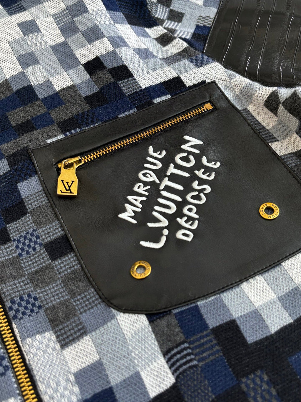 Front patch detail on blue-and-white check zip sweater jacket with gold zipper pull