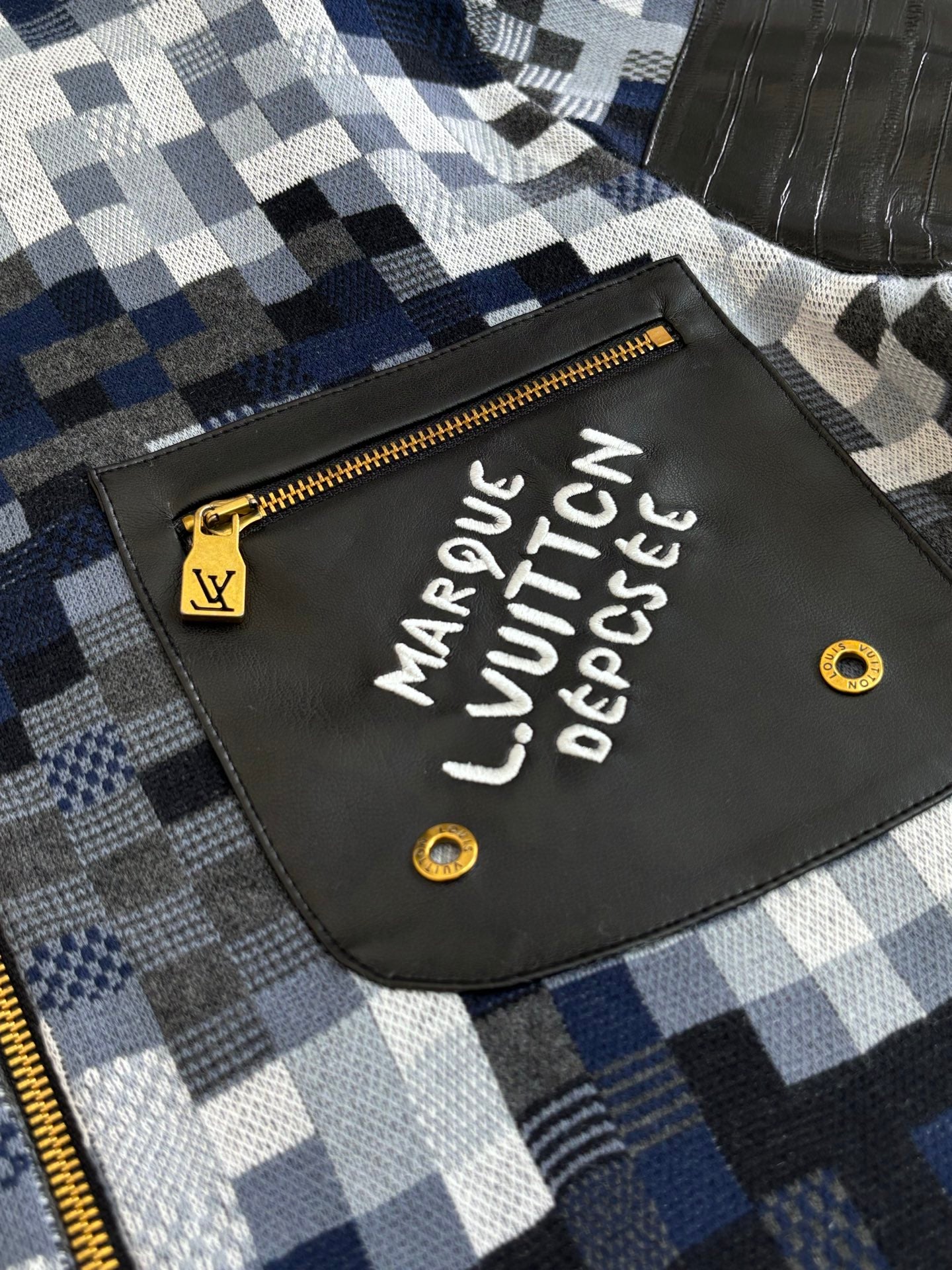 Front patch detail on blue-and-white check zip sweater jacket with gold zipper pull