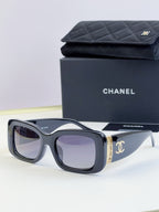 Square sunglasses with navy frames and tinted lenses, gold side logo detail