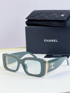 Square sunglasses with green frames and tinted lenses, gold side logo detail
