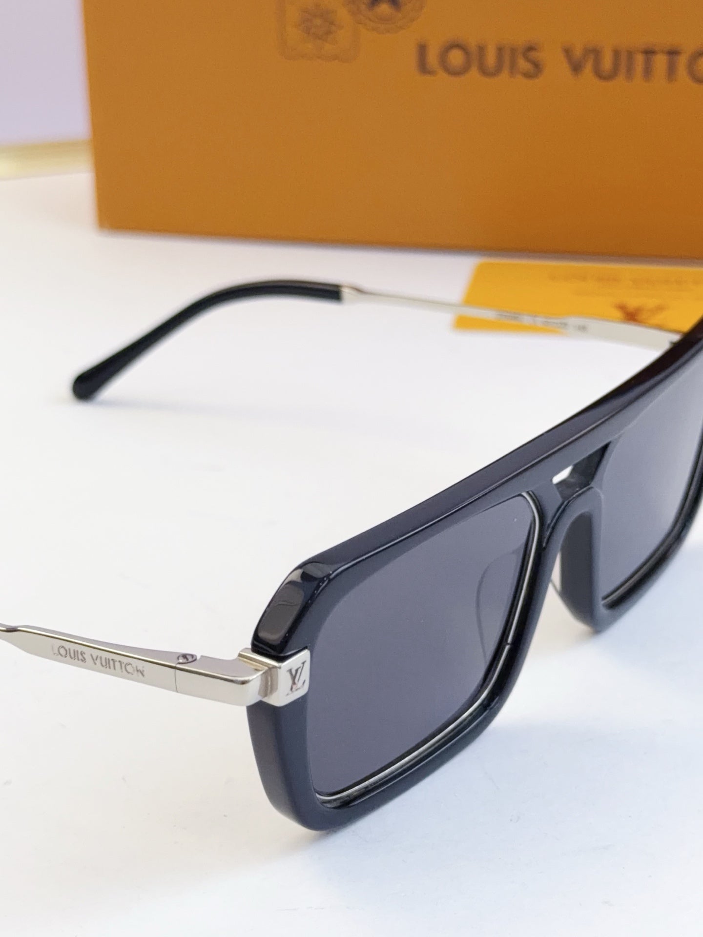 Louis Vuitton sunglasses close-up: black temple and metal hinge with dark lens