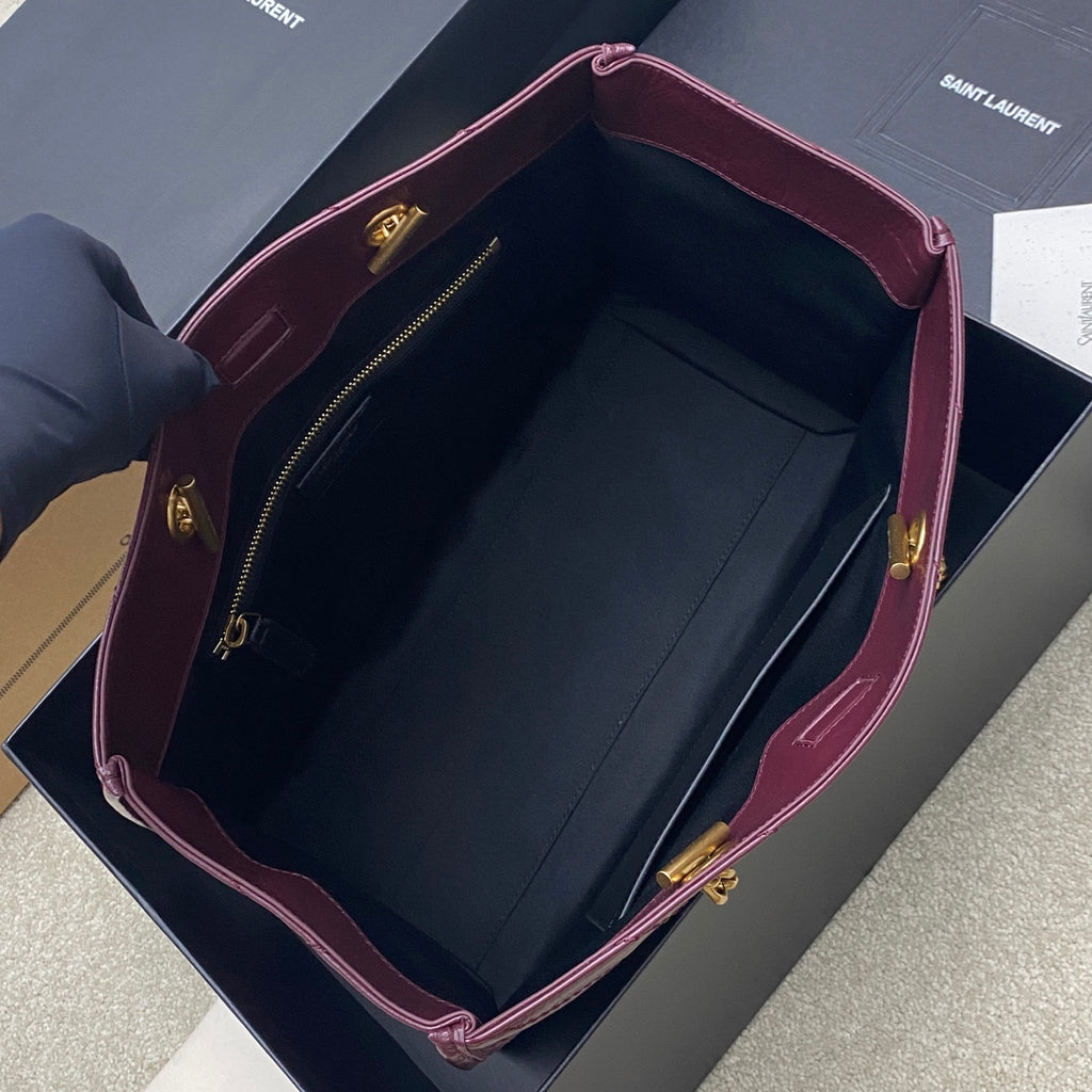 Open burgundy leather tote bag with dark interior lining and gold zipper hardware
