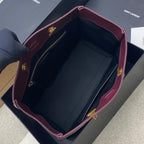 Open burgundy leather tote bag with dark interior lining and gold zipper hardware
