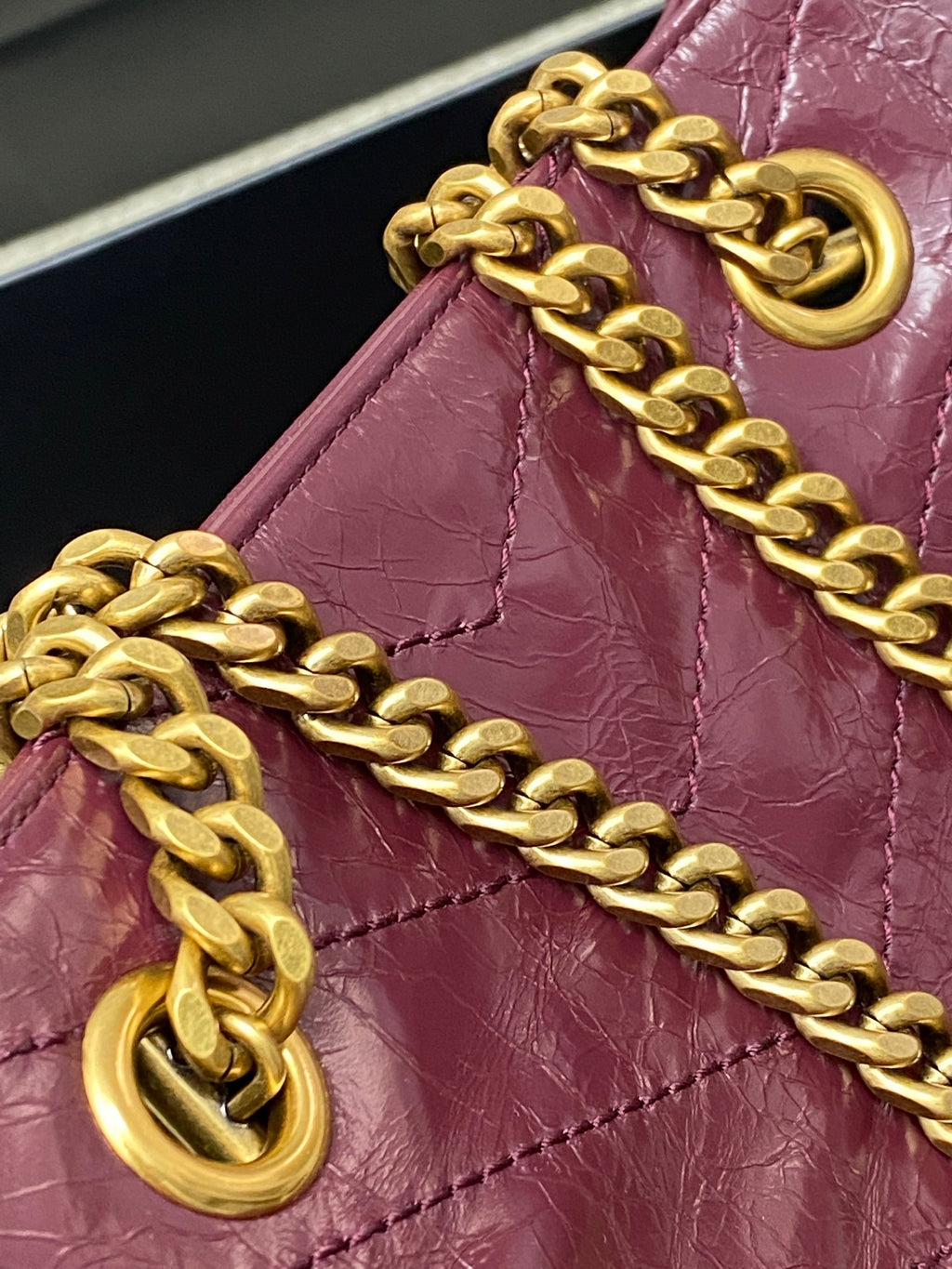 Gold chain strap and ring hardware attached to burgundy leather tote bag