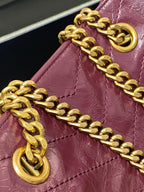 Gold chain strap and ring hardware attached to burgundy leather tote bag