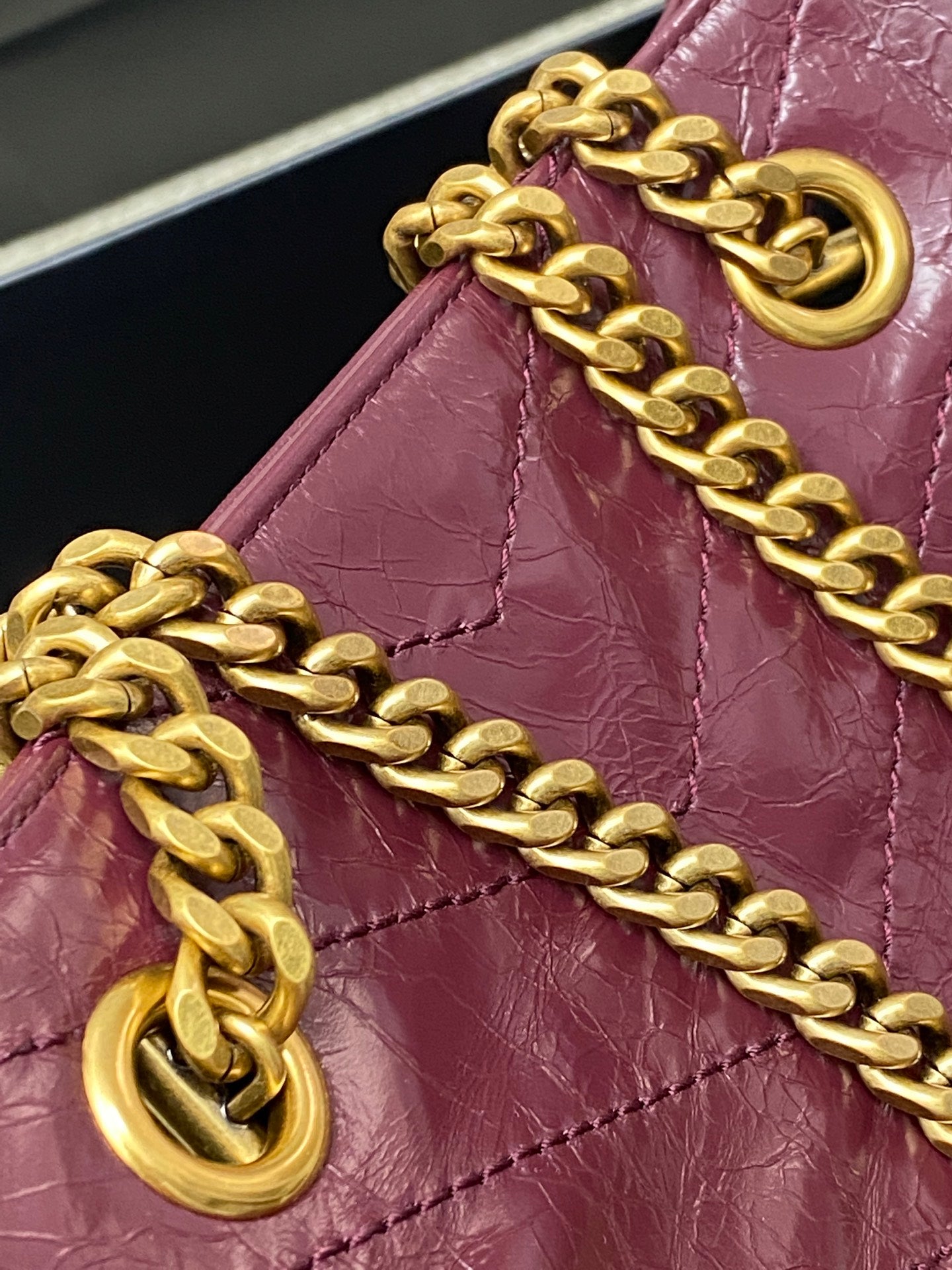 Gold chain strap and ring hardware attached to burgundy leather tote bag