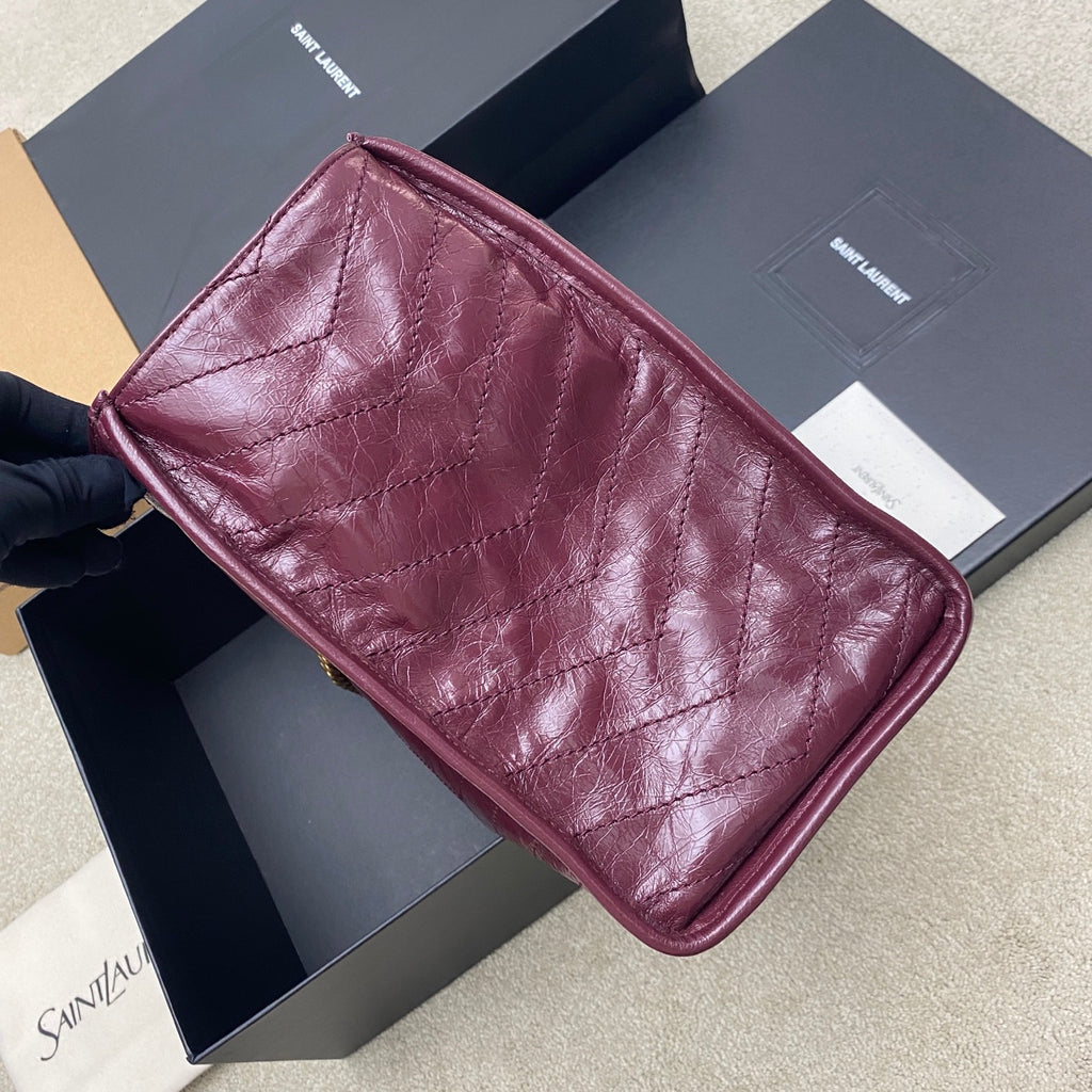 Burgundy leather tote bag with quilted diamond panels, side view and curved corners