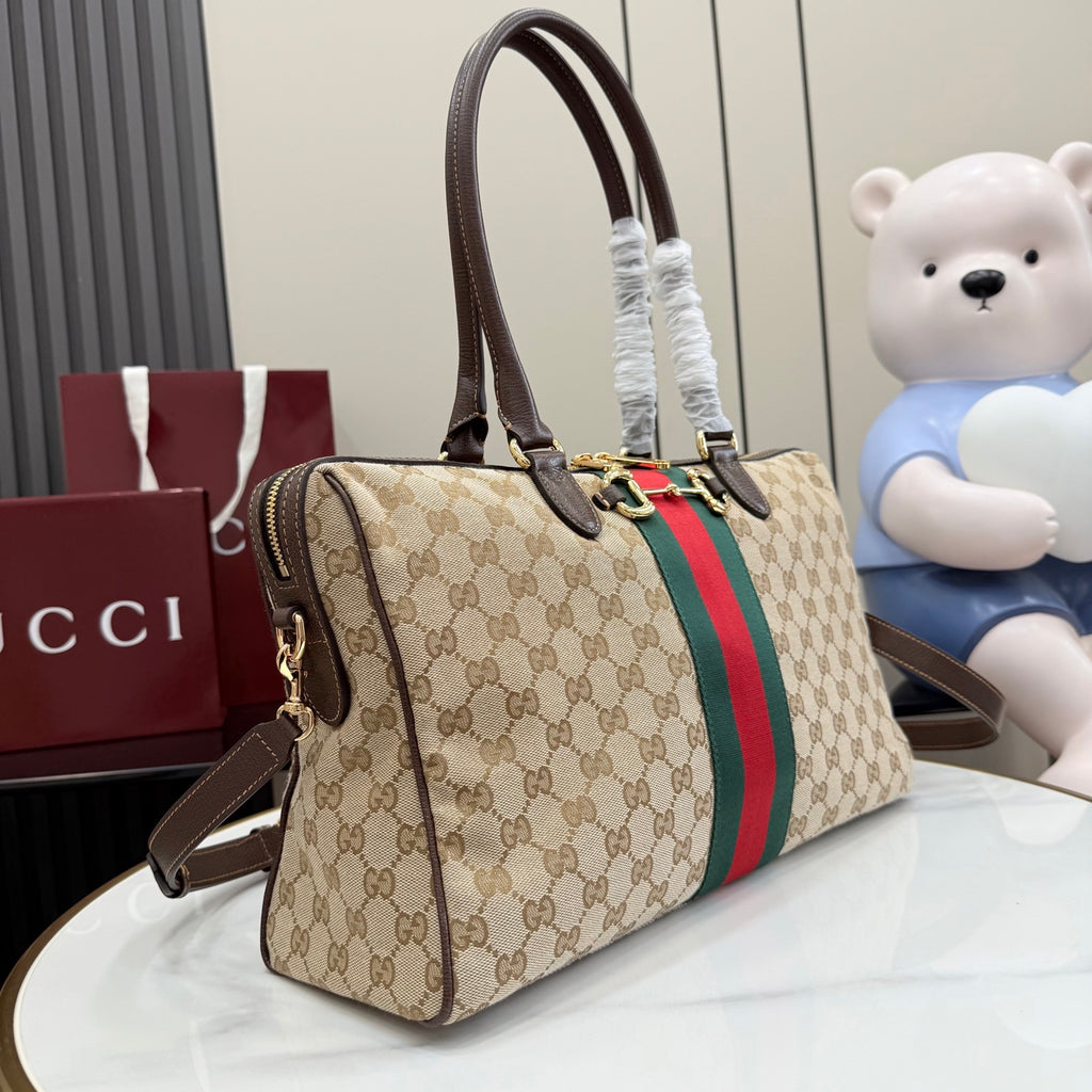 Gucci GG canvas satchel with dark brown handles, red/green stripe panel, crossbody strap.