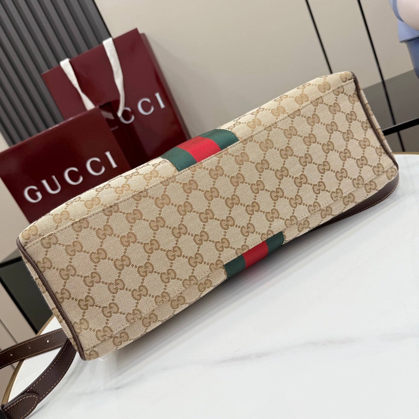 Gucci GG canvas shoulder bag with red/green stripe and dark brown trim, angled view.