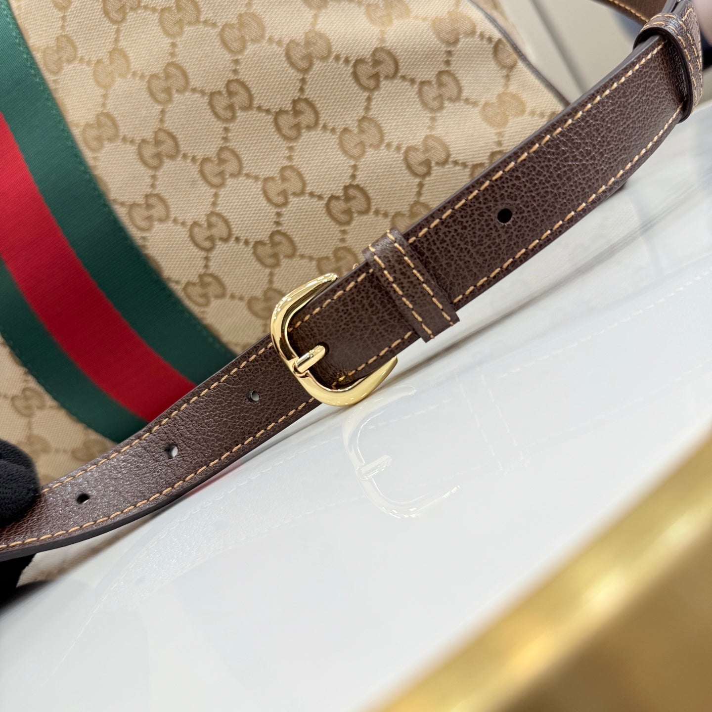Gucci bag with brown leather belt strap and gold-tone buckle on monogram canvas
