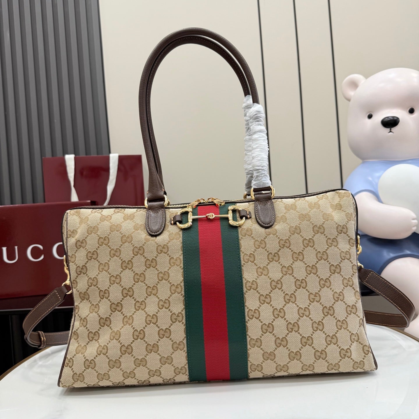 Gucci GG canvas tote bag with dark brown handles and red/green web stripe, gold hardware.