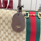 Gucci GG canvas bag with leather key fob marked "Made in Italy" and red/green web stripe.