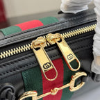 Gucci handbag zipper pull and gold-tone hardware on green-red stripe webbing.
