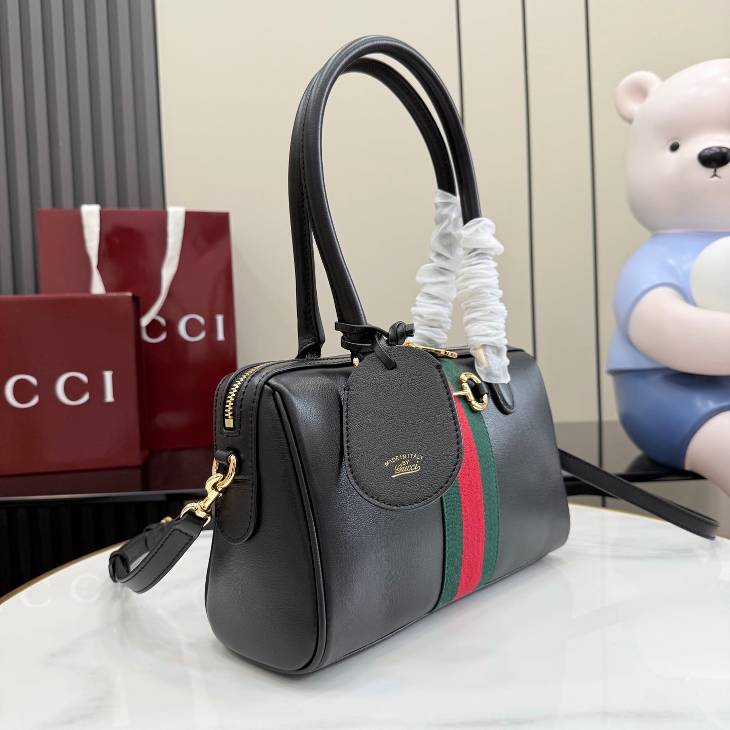 Black Gucci handbag with green-red web stripe, side strap, and gold-tone trim.