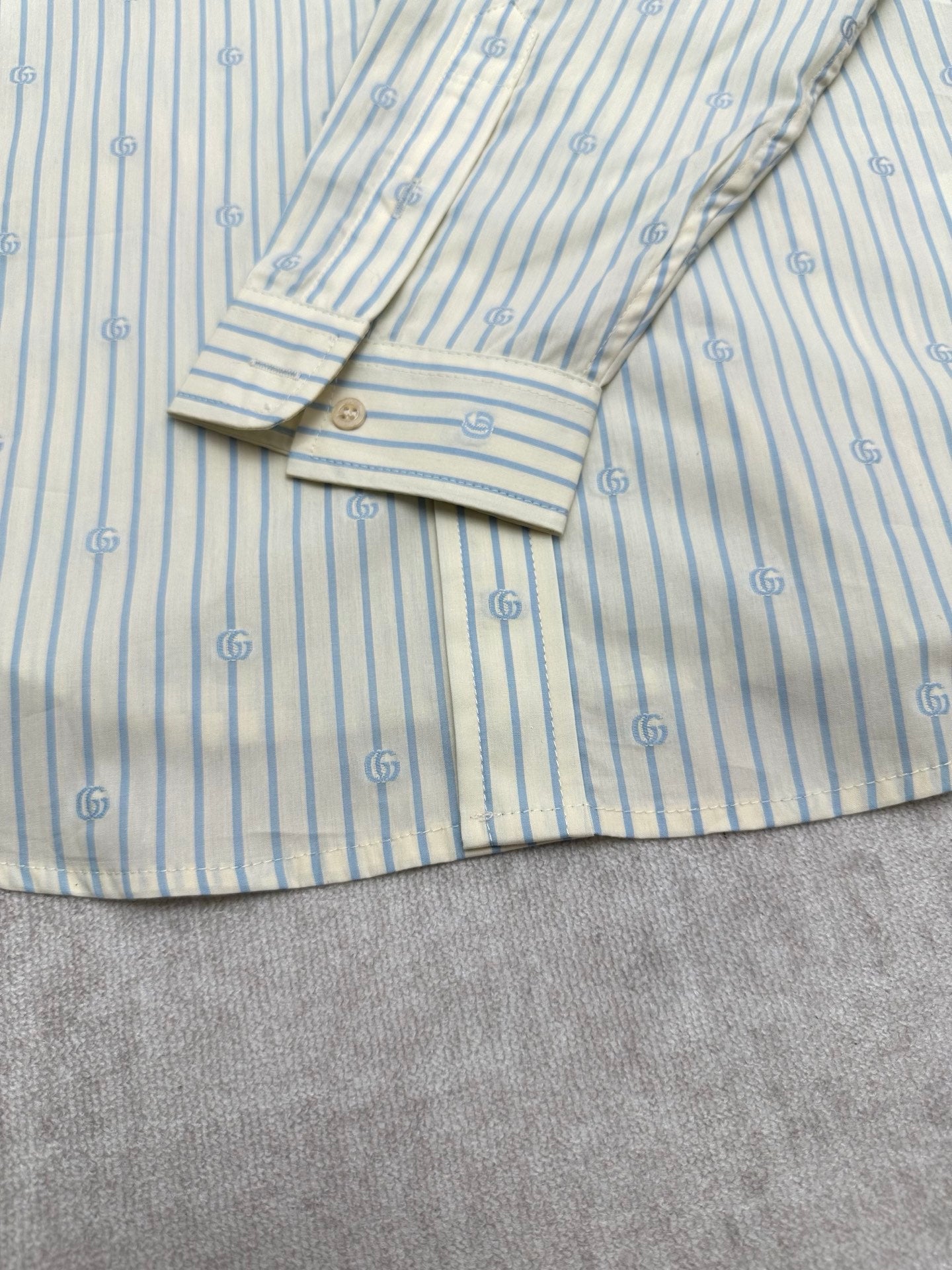 Light blue striped shirt cuff with button and folded sleeve detail