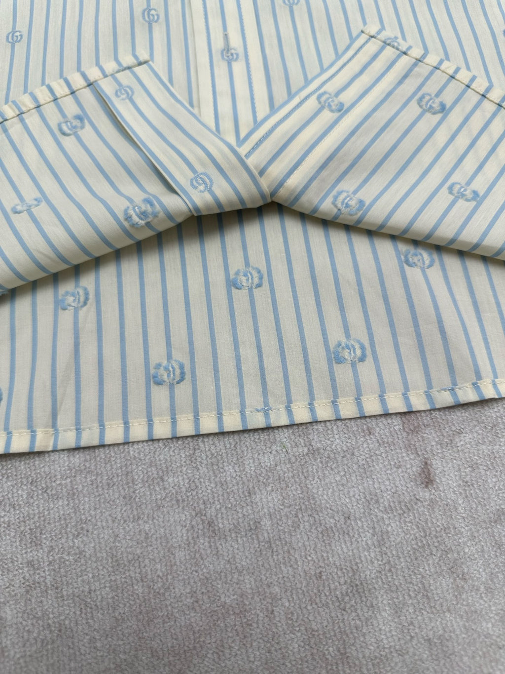 Light blue striped shirt with V-shaped yoke seam and small emblem print