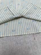 Light blue striped shirt with V-shaped yoke seam and small emblem print