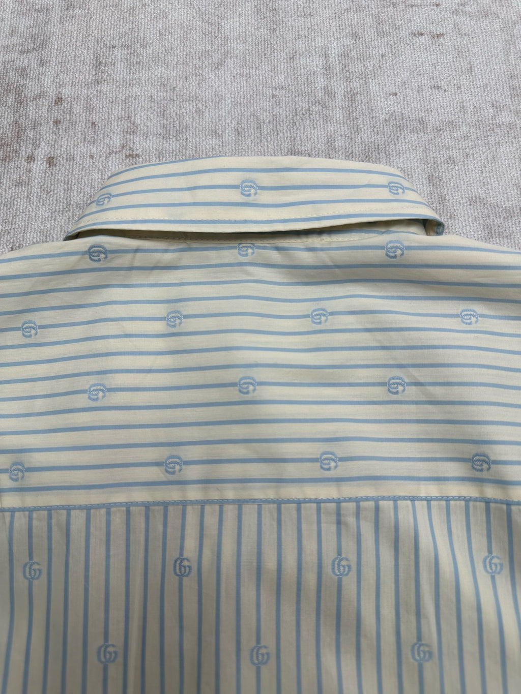Light blue striped shirt back with top button and small emblem pattern