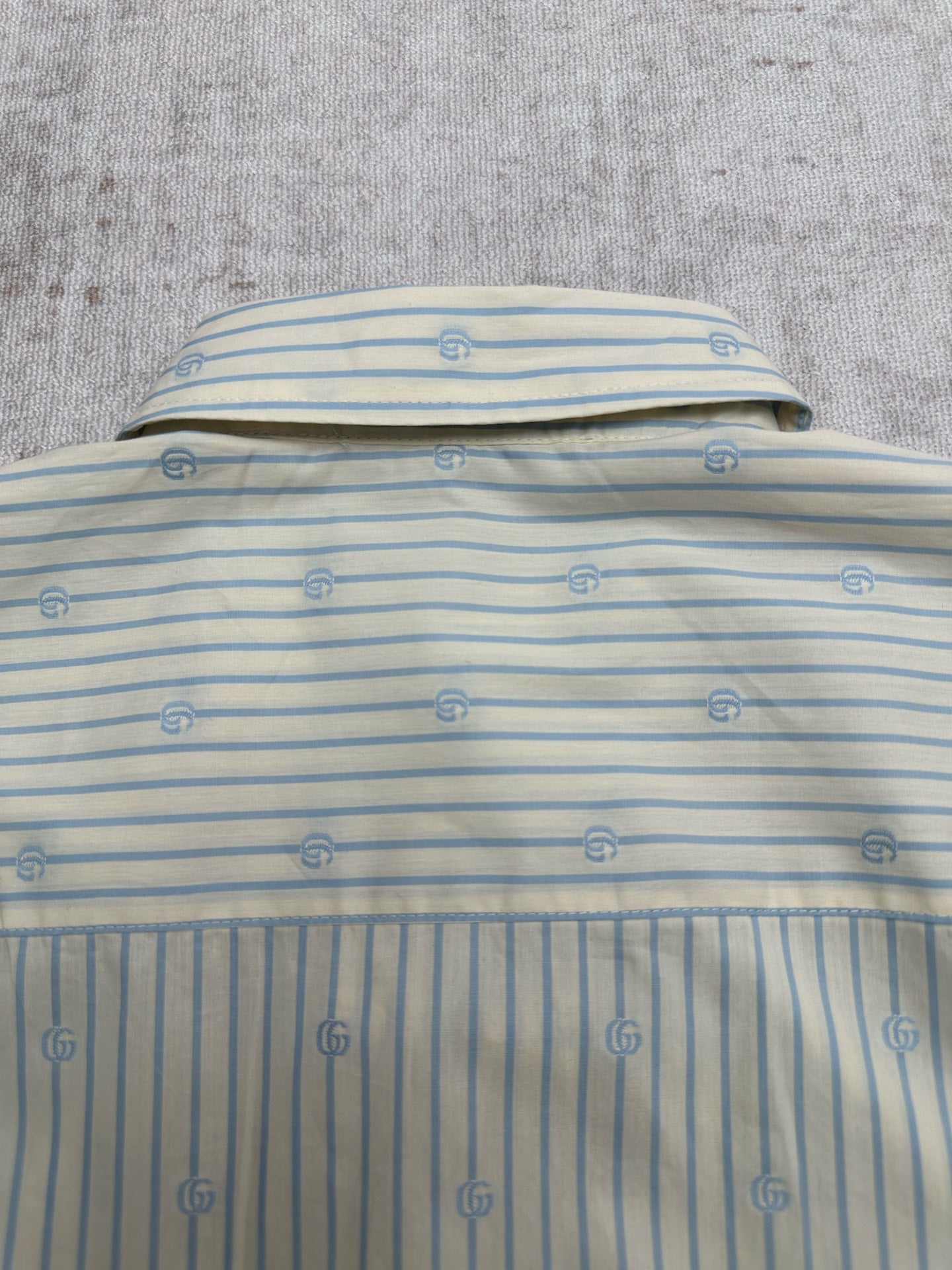 Light blue striped shirt back with top button and small emblem pattern