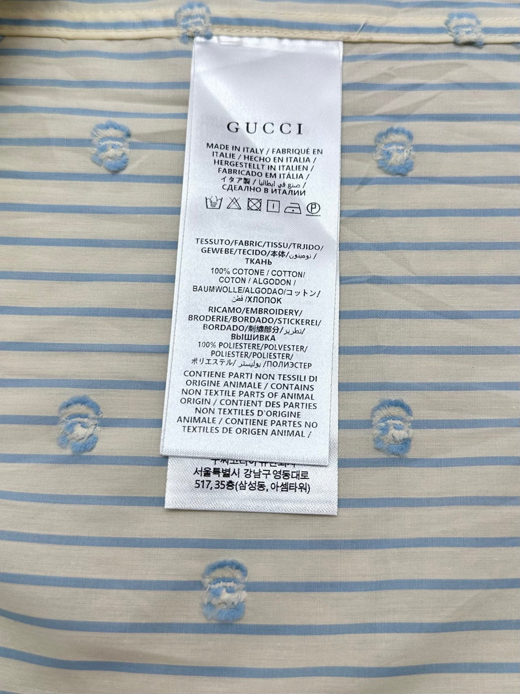 Gucci care label on light blue striped shirt fabric