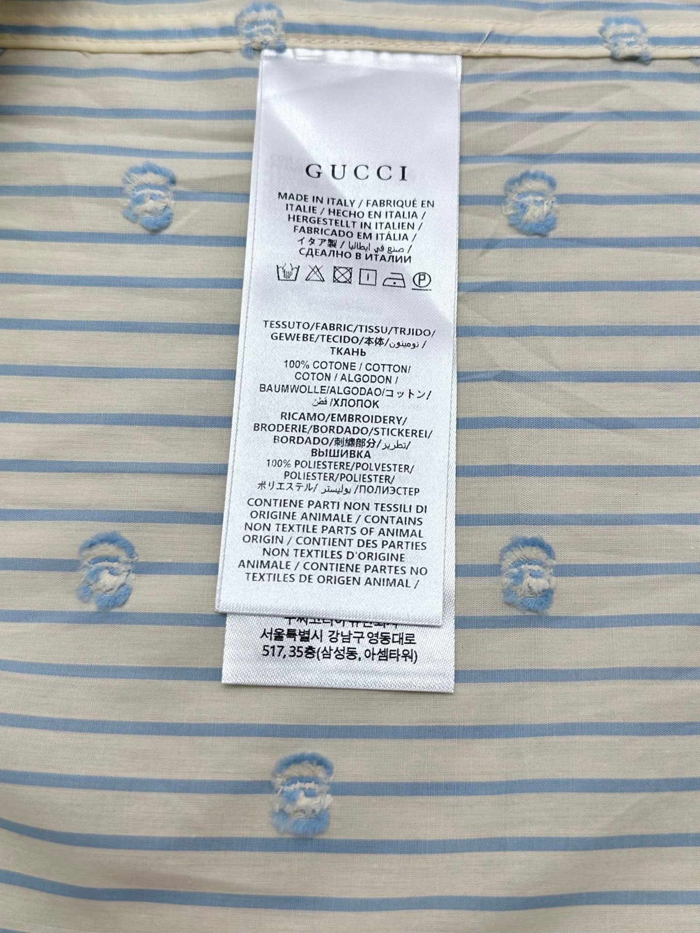Gucci care label on light blue striped shirt fabric