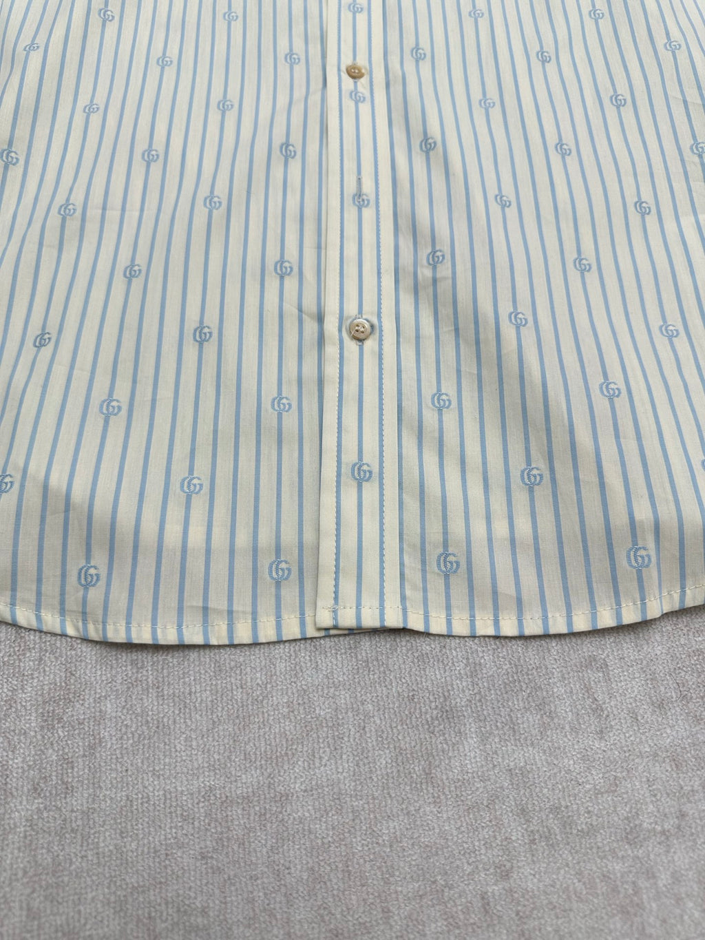 Light blue striped button-up shirt with vertical button placket and gold buttons
