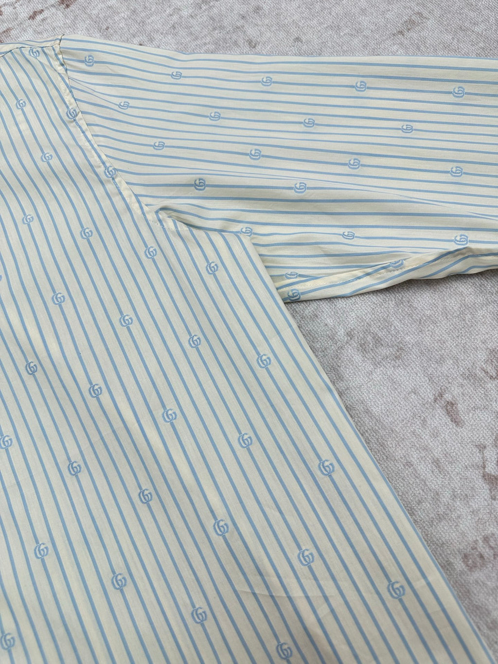 Light blue striped button-up shirt with small emblem pattern fabric detail