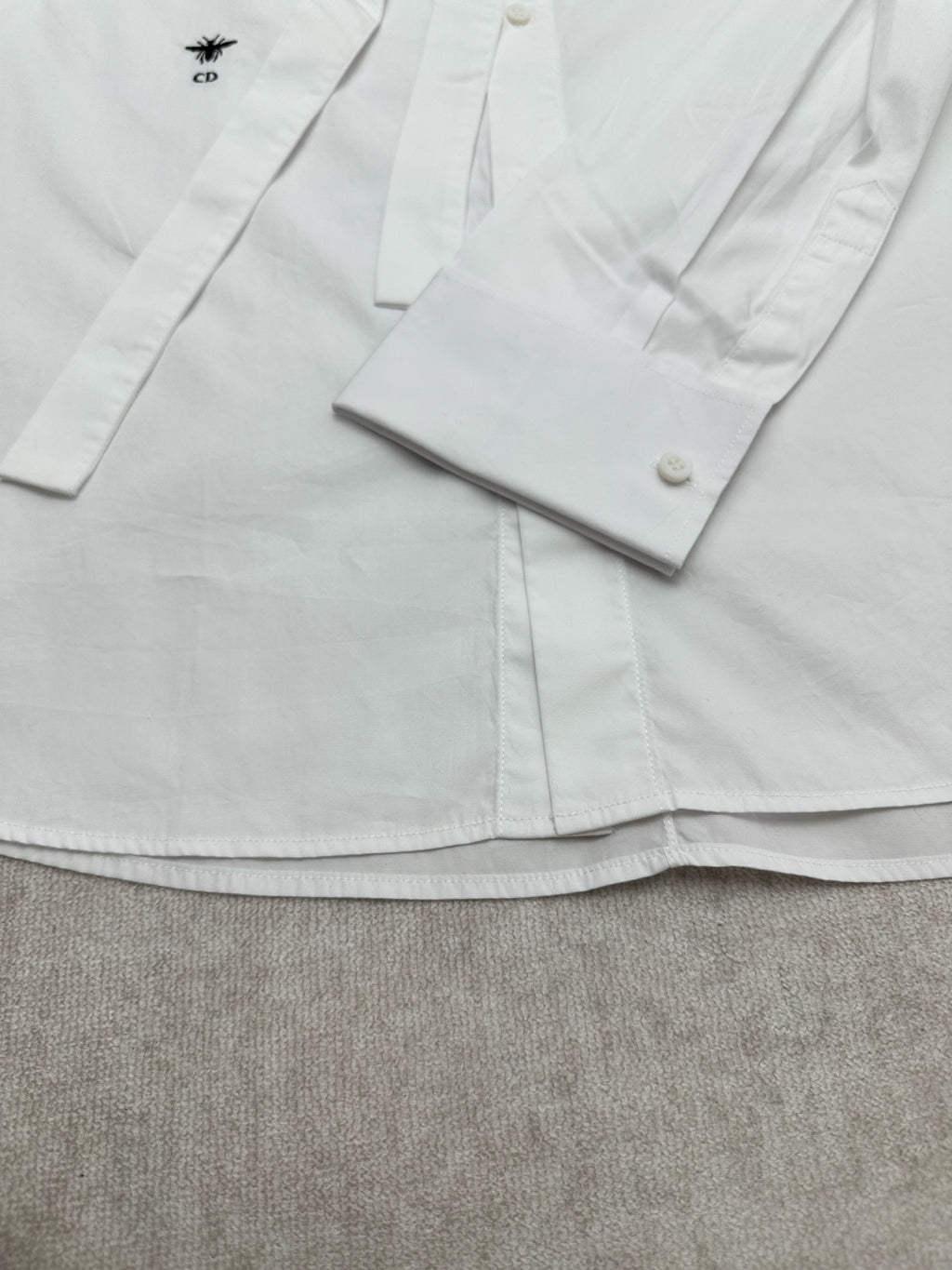 White shirt front with button placket and cuffs, small left chest logo