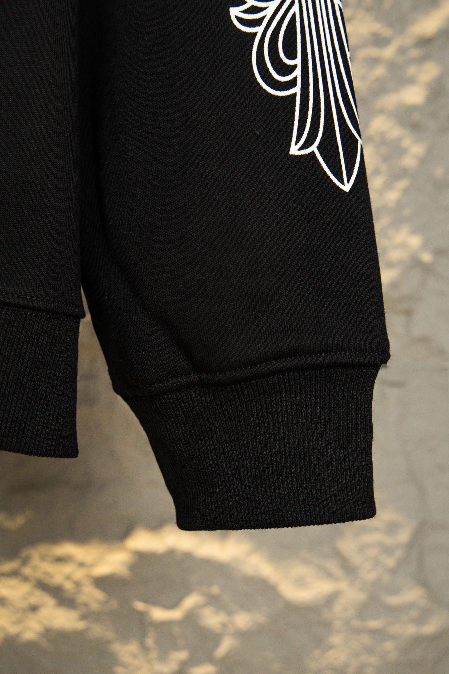 Black hoodie sleeve cuff with partial white wing-style logo