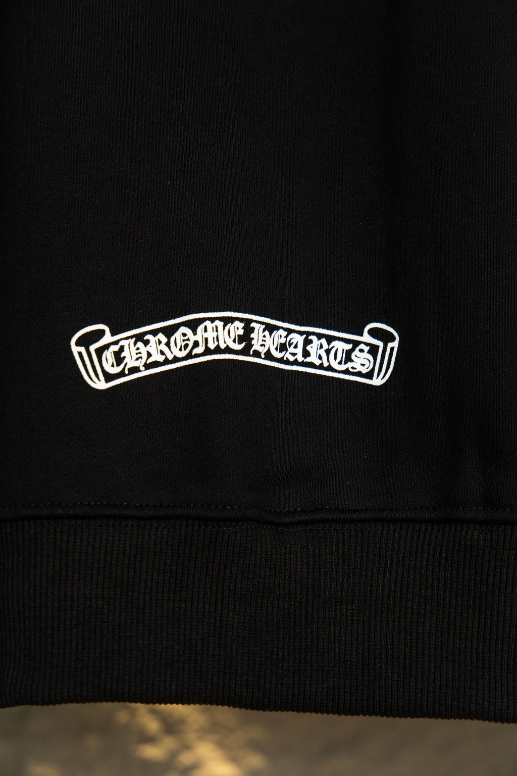 Black hoodie lower graphic text 'Chrome Hearts' in white