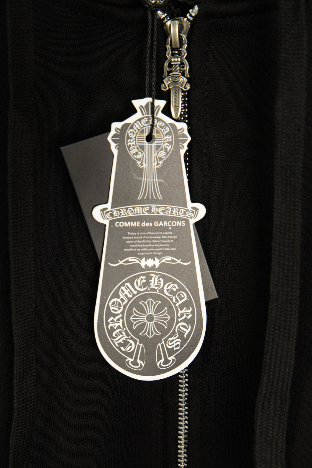 Black hoodie close-up with hanging logo tag on the front zipper